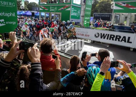 Gli spettatori che osservano l'inizio della gara ciclistica del Tour of Britain nel Birkenhead Park Foto Stock