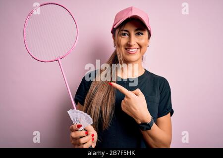 Giovane bella bruna sportivo donna che indossa il cappuccio giocando badminton tenendo racchetta molto felice puntando con mano e dito Foto Stock