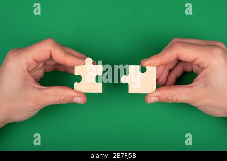 mano di gente che collega i puzzle su un background verde delle soluzioni di affari e rappresentano i concetti di aiuto e di sostegno del team, il successo e la strategia conce Foto Stock