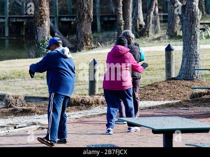 Un maschio due donne anziane persone che praticano Tia-Chi Chilly mattina presto tre persone Foto Stock