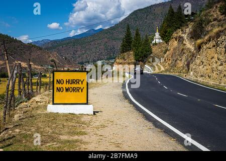 Messaggio di sicurezza stradale 'No rhay, No worry' sulla Paro-Thimphu Highway in Bhutan in una giornata di sole Foto Stock