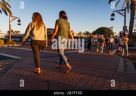 Giovani donne che visitano e attraversano una strada nel centro di Scottsdale, Arizona. Gli americani ignorano le distanze sociali. Foto Stock