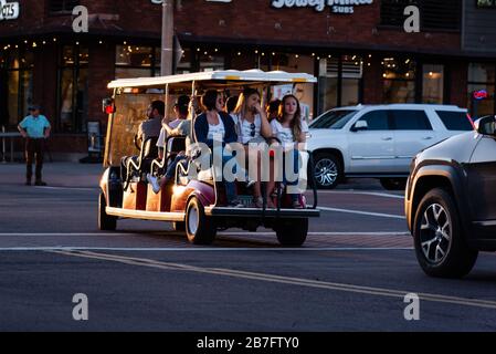 Una navetta elettrica piena di persone e tre donne sul retro in una strada trafficata nel centro di Scottsdale, Arizona. Gli americani ignorano le distanze sociali. Foto Stock