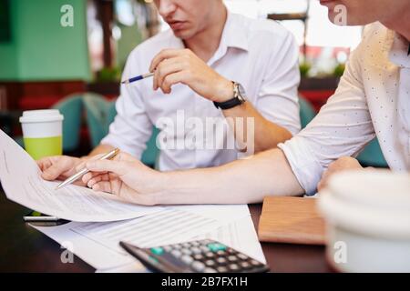 Giovani imprenditori seri che leggono il contratto o l'accordo durante la riunione e discutono i particolari e le correzioni Foto Stock