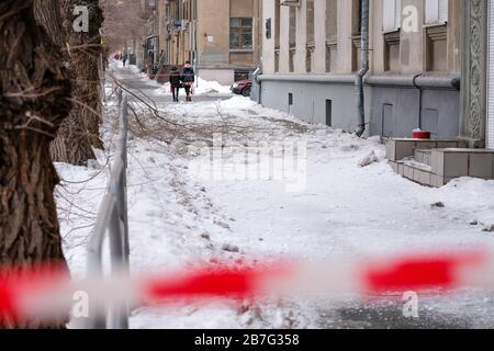 Passaggio bloccato. Rimozione della neve dal tetto di un edificio residenziale. Un nastro rosso blocca il percorso. Rimozione di neve e ghiaccio in primavera Foto Stock