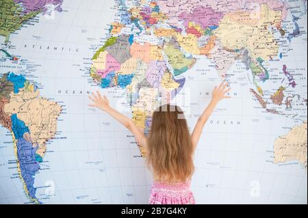 concetto mondiale di viaggio piccola ragazza in abito estivo con le mani in su vicino mappa del mondo