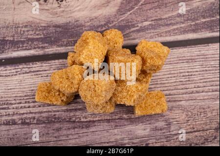 Un piccolo mucchio di grumi di zucchero marrone su uno sfondo di legno. Primo piano Foto Stock