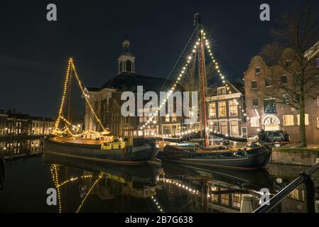 Vista panoramica notturna delle navi con decorazioni natalizie nel vecchio porto di Schiedam, Paesi Bassi. Foto Stock