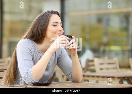 Donna soddisfatta che odora la sua tazza di caffè su una terrazza del ristorante Foto Stock