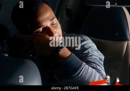 Un conducente stanco dorme e riposa all'interno della sua auto Foto Stock