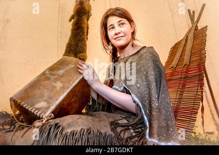 Giovane Lakota si siede sorridendo in una tipi e fa una scatola di rafide Foto Stock