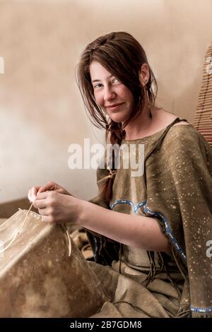 Giovane Lakota si siede sorridendo in una tipi e fa una scatola di rafide Foto Stock