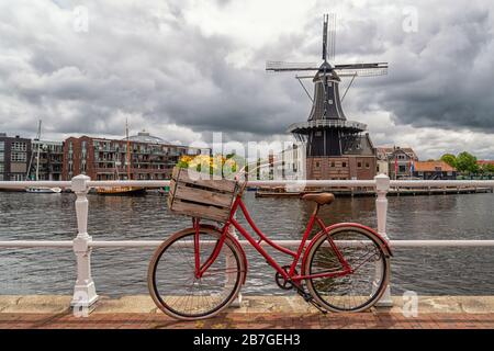 Bici rossa davanti al Molen De Adriaan ad Haarlem Foto Stock