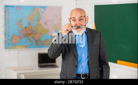 Altri strumenti introdotti nelle aule di tutti i giorni. Insegnante di uomo anziano alla lavagna. Ritorno a scuola. Insegnante di vecchia generazione di scuola. Docente esperto. Insegnante maturo godendo il lavoro. Condivisione delle conoscenze. Foto Stock