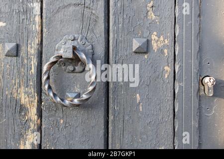 Maniglia della porta attorcigliata su porta in legno. La maniglia della porta è in ferro ed è nera. Foto Stock