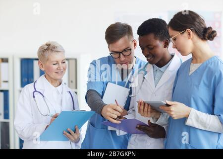 Gruppo multietnico di medici che tiene le graffette mentre si trova all'interno dell'ufficio medico Foto Stock