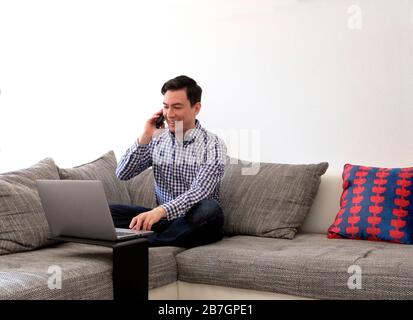 Uomo che lavora da casa con un computer portatile nel soggiorno Foto Stock