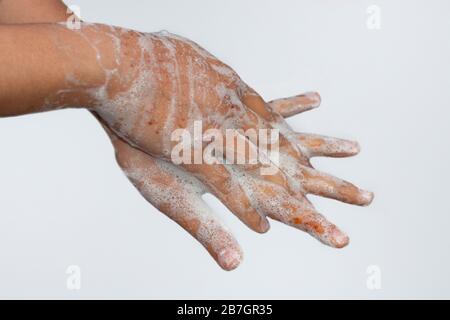 Una ragazza asiatica lavando le mani con sapone isolato con sfondo bianco. Concetto di igiene. Prevenire dal virus corona (covid-19). Messa a fuoco selettiva. Foto Stock