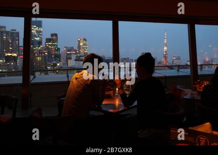 Coppia giapponese che si è data in un romantico bar con una bella vista notturna sulla città di Tokyo Foto Stock