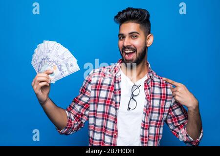 Ritratto di bel giovane uomo che mostra banconote in piedi su sfondo blu Foto Stock