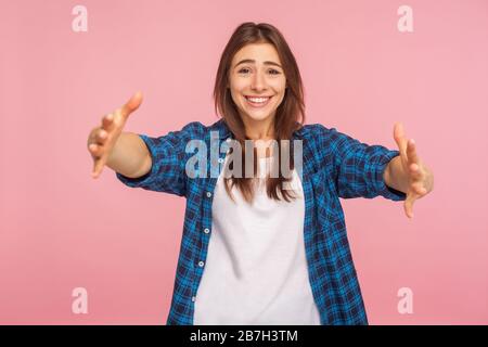 Permettetemi di abbracciarvi! Ritratto di ragazza gentile-hearted in camicia a scacchi che apre le sue braccia per abbracciare voi, accogliendo con il sorriso toothy, condividendo l'amore. indo Foto Stock