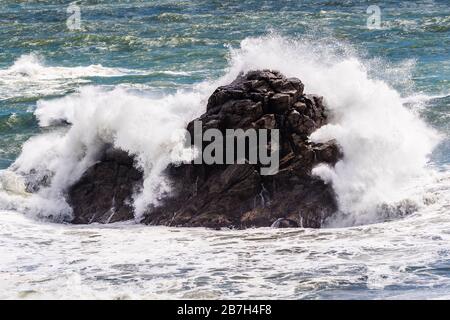 Onde che si infrangono sulle rocce a Tauranga Bay, West Coast, Nuova Zelanda Foto Stock