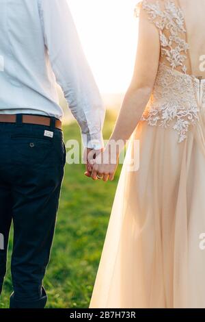 Immagine ritagliata di bella coppia felice di matrimonio tenendo le mani, mentre trascorrere il tempo in primavera giardino, campo o parco. Amore, emozioni, data e matrimonio Foto Stock