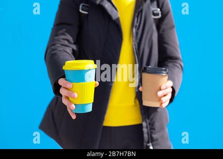 Una persona che detiene take away caffè tazza una carta monouso altro uno è riutilizzabile Foto Stock