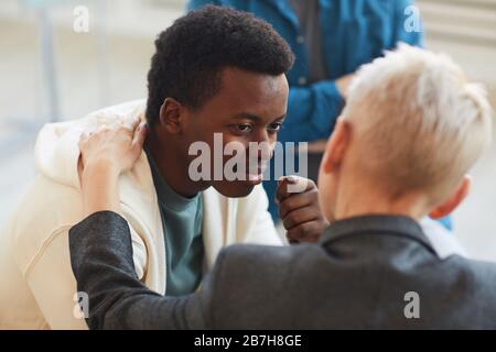 Vista ad alta angolazione al giovane uomo afro-americano sorridente con gratitudine allo psicologo mentre, mentre in gruppo di sostegno cerchio, copia spazio Foto Stock