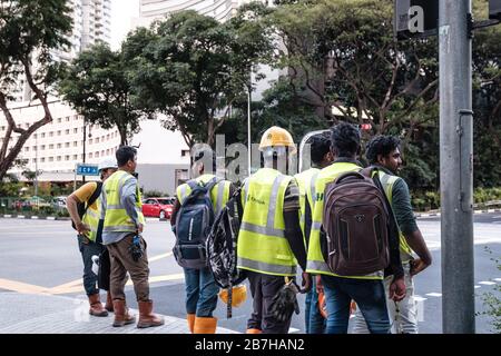 Singapore-13 MAR 2020:lavoratori di strada in attesa di attraversare la città strada Foto Stock