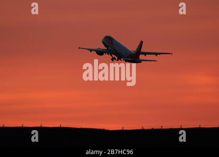 15 marzo 2020, Brandeburgo, Schönefeld: Un Airbus A320-200 Sharklet della compagnia aerea easyJet decollo dall'aeroporto di Schönefeld di fronte al cielo rosso sera verso Londra. Foto: Soeren Stache/dpa-Zentralbild/ZB Foto Stock