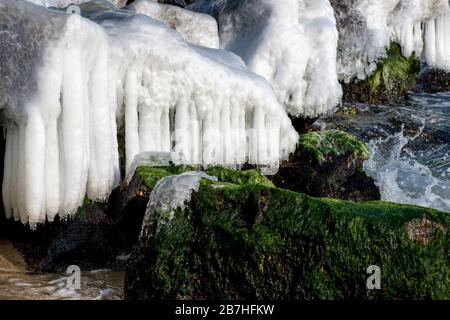 L'inverno si disegna su rocce marine e ghiaccioli Foto Stock
