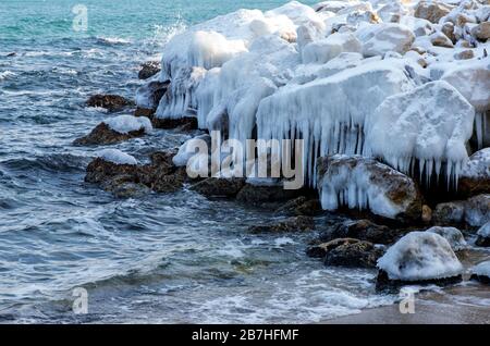 L'inverno si disegna su rocce marine e ghiaccioli Foto Stock