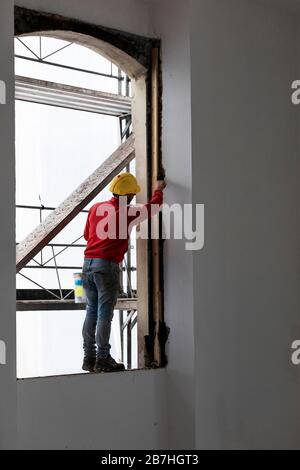 Worker bilanciamento su una finestra durante il lavoro. Cantiere Foto Stock