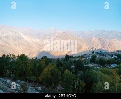 Villaggio fiancheggiato da campi, alta montagna himalayana, e gli alberi nella valle di Spiti all'alba a Nako, Himachal Pradesh, India. Foto Stock