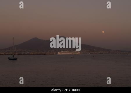 La luna che sorge dietro il Vesuvio a Napoli Foto Stock