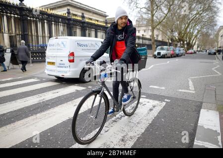 Londra, Inghilterra, Regno Unito. Uomo in bicicletta a cavallo su una traversata pedonale di fronte al British Museum Foto Stock