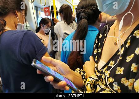 Bangkok, Thailandia - 14 marzo 2020 : i passeggeri asiatici nel trasporto pubblico del treno sopraelevato indossano la maschera igienica facciale andare al lavoro e controllare le notizie pandemiche Foto Stock