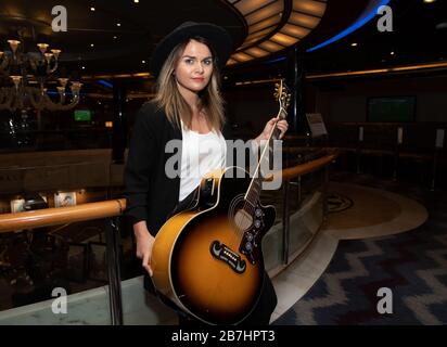 Angela Grace Brown, cantante e chitarrista, posa nell'atrio a bordo di Oceana Foto Stock