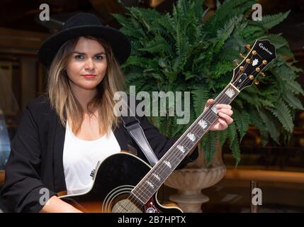 Angela Grace Brown, cantante e chitarrista, posa nell'atrio a bordo di Oceana Foto Stock