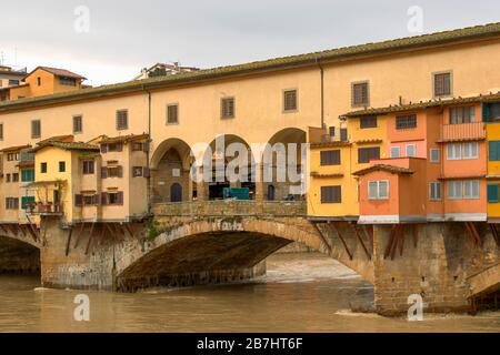 FIRENZE PONTE VECCHIO E CASE O NEGOZI CHE ATTRAVERSANO IL FIUME ARNO IN PIENA Foto Stock