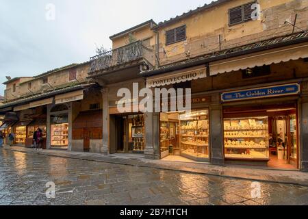 FIRENZE ITALIA PIOGGIA SUL PONTE VECCHIO E NEGOZI DI OREFICERIA O ARGENTERIA CHE ATTRAVERSANO IL FIUME Foto Stock