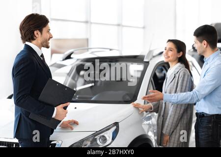 Concessionario che mostra Young Couple New Auto nel Dealership Store Foto Stock