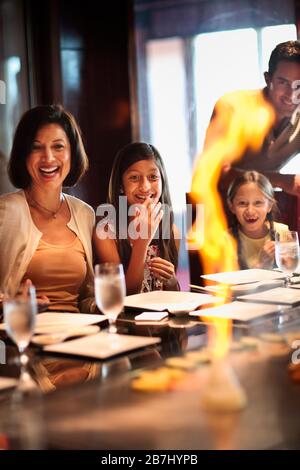 La famiglia a un giapponese ristorante teppanyaki, guardare lo chef fuoco la piastra. Foto Stock