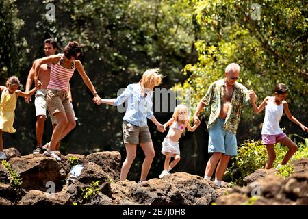 La famiglia e gli amici escursionismo su terreno roccioso e tenendo le mani. Foto Stock