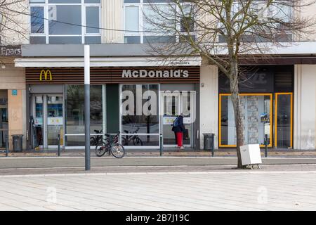 Chartres, Francia - 15 marzo 2020: Un uomo controlla la porta di un ristorante McDonald's chiuso insolitamente dopo che il governo francese ha ordinato l'l parziale Foto Stock