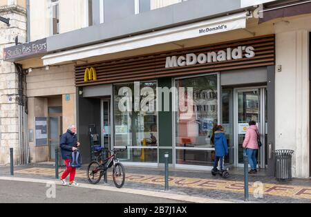 Chartres, Francia - 15 marzo 2020: Una donna controlla la porta di un ristorante McDonald's chiuso insolitamente dopo che il governo francese ha ordinato la parte Foto Stock