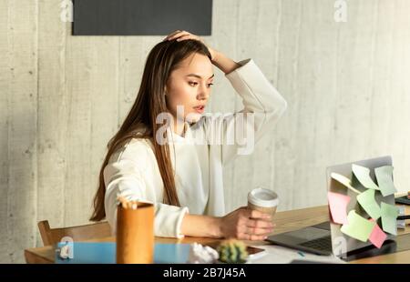 Donna freelance in shock e tenendo la testa Foto Stock