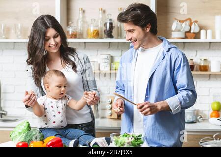 I genitori preparano il pranzo con il figlio del bambino alla cucina Foto Stock