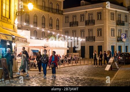 I turisti passeggiano per le strade acciottolate di notte nel quartiere di Alfama, Lisbona, Portogallo Foto Stock